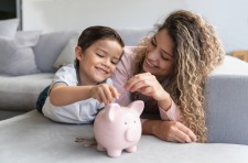 kid putting coins in a piggy bank